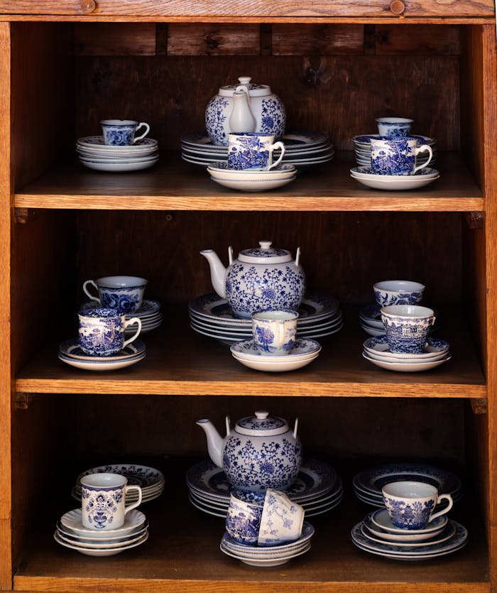 about-us-02 Elegant vintage blue and white porcelain tea set displayed on wooden shelves.